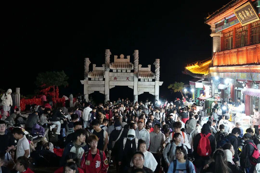 泰山五一假期凌晨挤满游客,人人身穿御寒服看日出,有餐厅售卖夜间休息位60元可坐两小时,酒店太空舱388元一晚